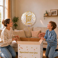 Moeder en jongen bekijken een Best Day Ever-ballon van 45 cm met gouden letters en confetti boven een geopende cadeaudoos.