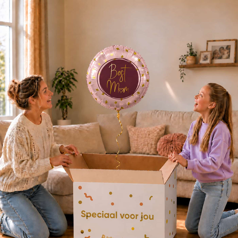 Moeder en meisje bekijken een roze Best Mom-ballon van 45 cm met gouden hartjes boven een geopende cadeaudoos.