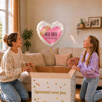 Moeder en meisje bekijken een hartvormige Heel Veel Beterschap-ballon van 43 cm met een roze hart en pleister boven een geopende cadeaudoos.