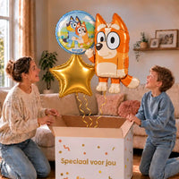 Bingo Bluey Trosje: moeder en zoon pakken het heliumgevulde ballonnentrosje uit een Speciaal voor jou-doos, met natuurlijk gekrulde gouden linten.