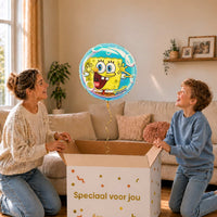Moeder en jongen bekijken de ballon Blije Spongebob Helium Ballon in zacht warm licht boven de geopende cadeaudoos ‘Speciaal voor jou’.