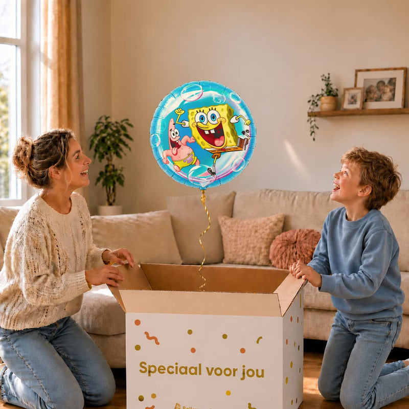 Moeder en jongen bekijken de ballon Blije Spongebob & Patrick Ballon in zacht warm licht boven de geopende cadeaudoos ‘Speciaal voor jou’.