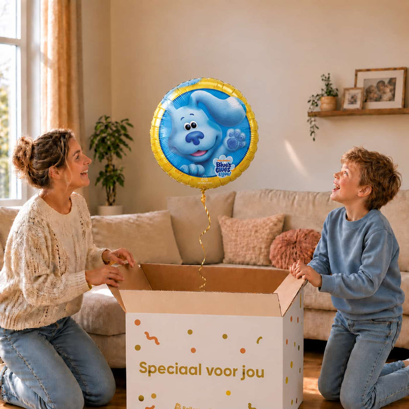 Moeder en jongen bekijken een Blue’s Clues-ballon van 46 cm met de blauwe hond en gele rand boven een geopende cadeaudoos.