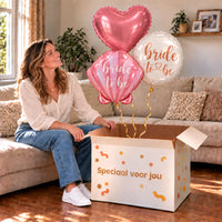 Een feestelijk huwelijksmoment met Bride To Be Trosje Ballonnen boven een open Speciaal voor jou-doos in een warme woonkamer.