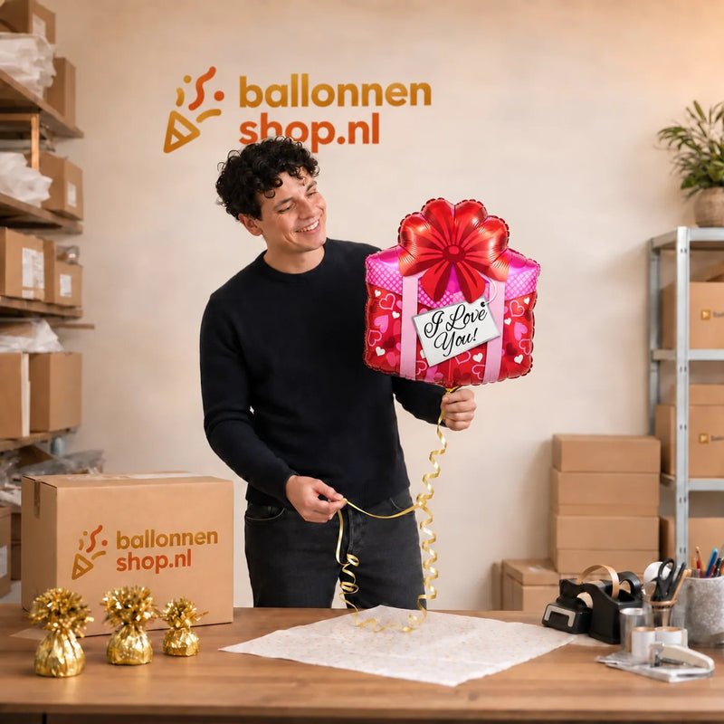 Jesse houdt de I Love You Cadeau ballon vast in de warme werkplaats van Ballonnenshop.nl.