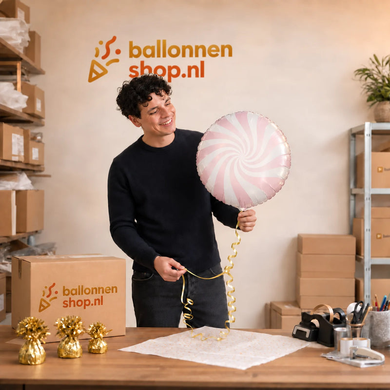 Jesse houdt de Candy Licht Roze Helium Ballon vast in de warme werkplaats van Ballonnenshop.nl.