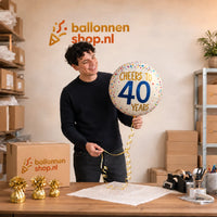 Jesse houdt de Cheers To 40 Years Helium Ballon vast in de warme werkplaats van Ballonnenshop.nl.