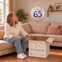 Vrouw viert 65 jaar met Cheers To 65 Years Helium Ballon uit een cadeaudoos van Ballonnenshop.nl