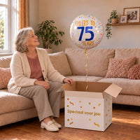 Vrouw viert 75 jaar met Cheers To 75 Years Helium Ballon uit een cadeaudoos van Ballonnenshop.nl