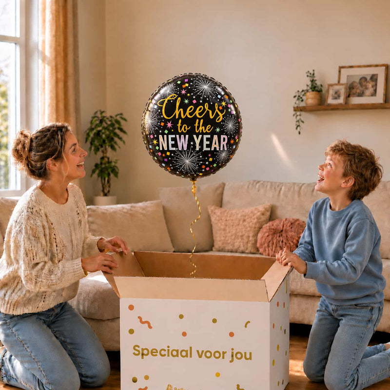 Moeder en jongen bekijken een zwarte Cheers to the New Year-ballon van 45 cm met vuurwerk en confetti boven een cadeaudoos.