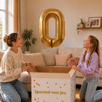 Cijfer 0 Helium Ballon Goud zweeft boven een geopende cadeaudoos bij een moeder en meisje in een warme woonkamer.