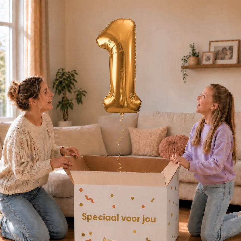Cijfer 1 Helium Ballon Goud zweeft boven een geopende cadeaudoos bij een moeder en meisje in een warme woonkamer.