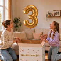 Cijfer 3 Helium Ballon Goud zweeft boven een geopende cadeaudoos bij een moeder en meisje in een warme woonkamer.