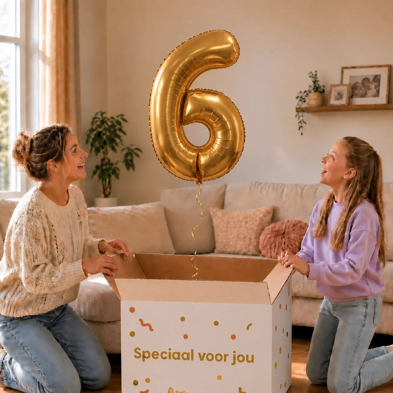 Cijfer 6 Helium Ballon Goud zweeft boven een geopende cadeaudoos bij een moeder en meisje in een warme woonkamer.