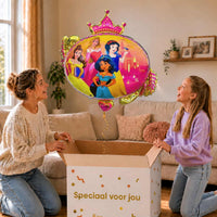 Moeder en meisje bekijken een Disney-prinsessenballon met Doornroosje, Belle, Sneeuwwitje en Jasmine van 86 cm met gouden lint boven de geopende cadeaudoos ‘Speciaal voor jou’.