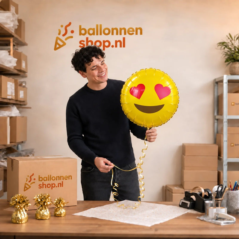 Jesse houdt de Emoji Hartjes Ogen Helium Ballon vast in de warme werkplaats van Ballonnenshop.nl.