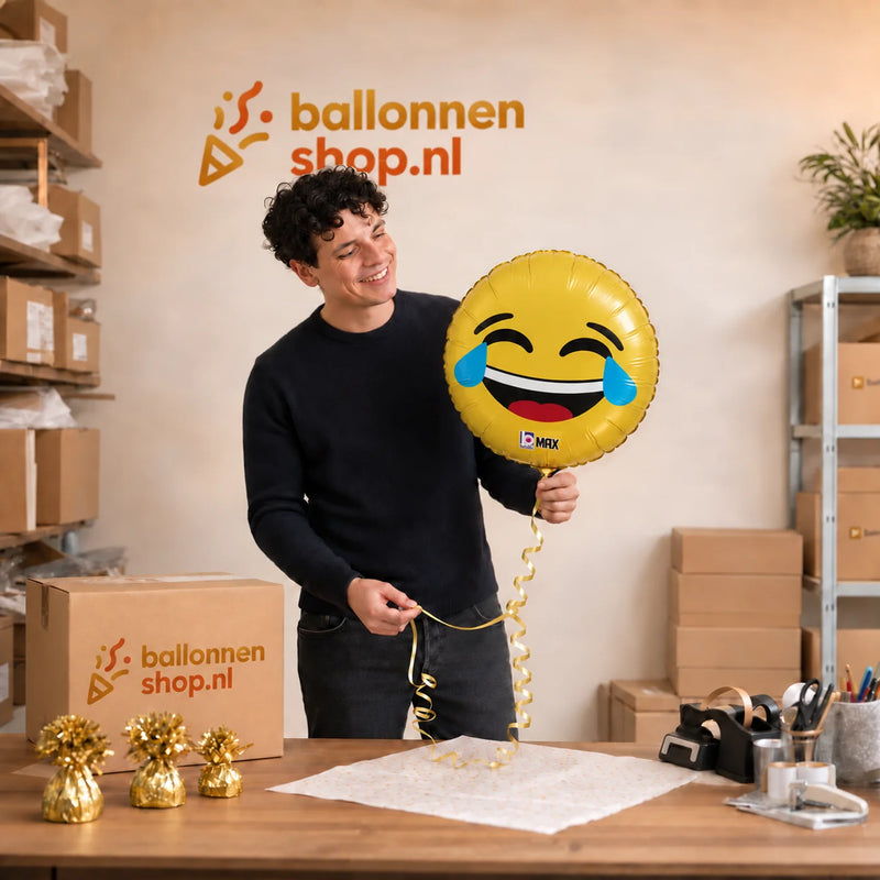 Jesse houdt de Emoji Lol Helium Ballon vast in de warme werkplaats van Ballonnenshop.nl.