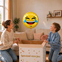 Moeder en jongen bekijken een gele Emoji LOL-ballon van 45 cm met blauwe lachtranen boven een cadeaudoos.