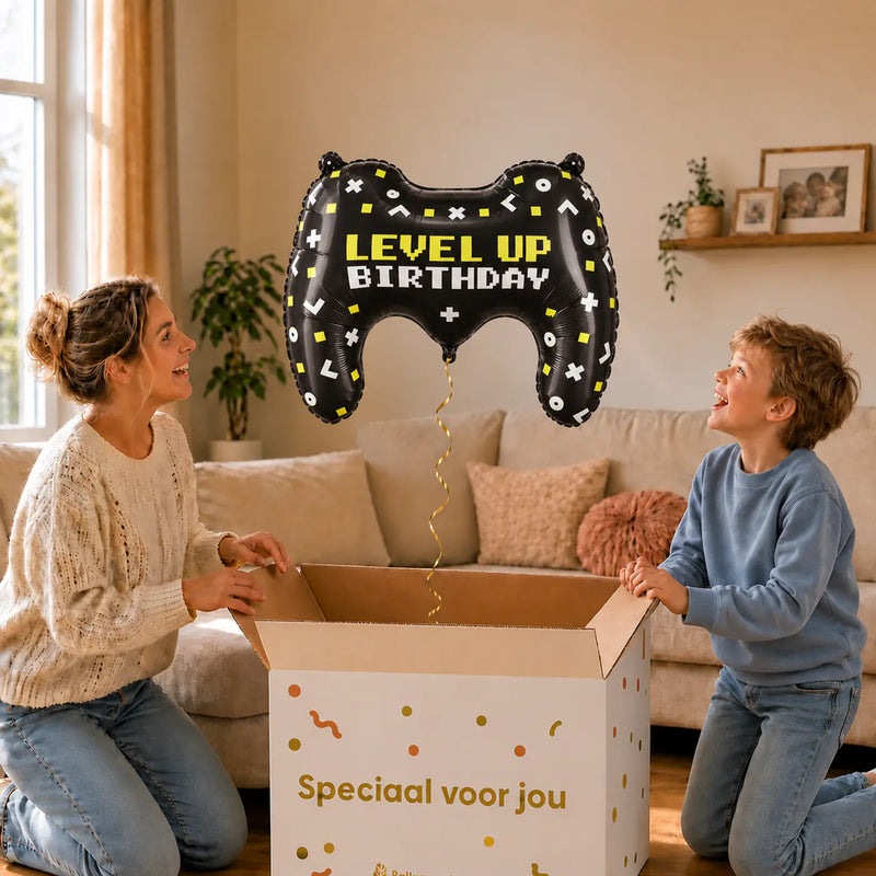 Gamecontroller Level Up XL Ballon – uitpakmoment met moeder en jongetje in een warme woonkamer – Ballonnenshop.nl
