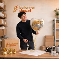 Jesse houdt de Geslaagd You Did It Helium Ballon vast in de warme werkplaats van Ballonnenshop.nl.