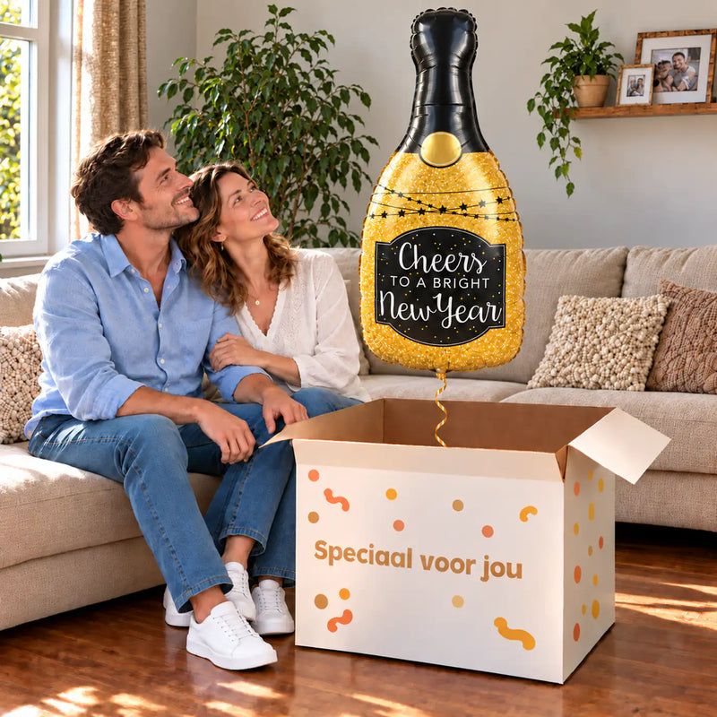 Een volwassen stel kijkt blij naar Glittering New Year XL Ballon boven een grote Speciaal voor jou-doos in een warme woonkamer.