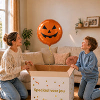 Moeder en jongen bekijken een oranje Halloween-pompoenballon van 45 cm boven de geopende cadeaudoos.