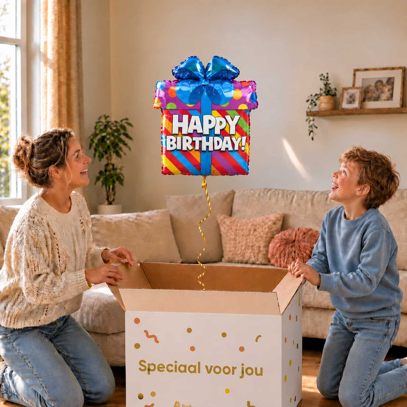 Moeder en jongen bekijken een kleurrijke Happy Birthday-cadeauballon met blauwe strik boven de geopende cadeaudoos ‘Speciaal voor jou’.