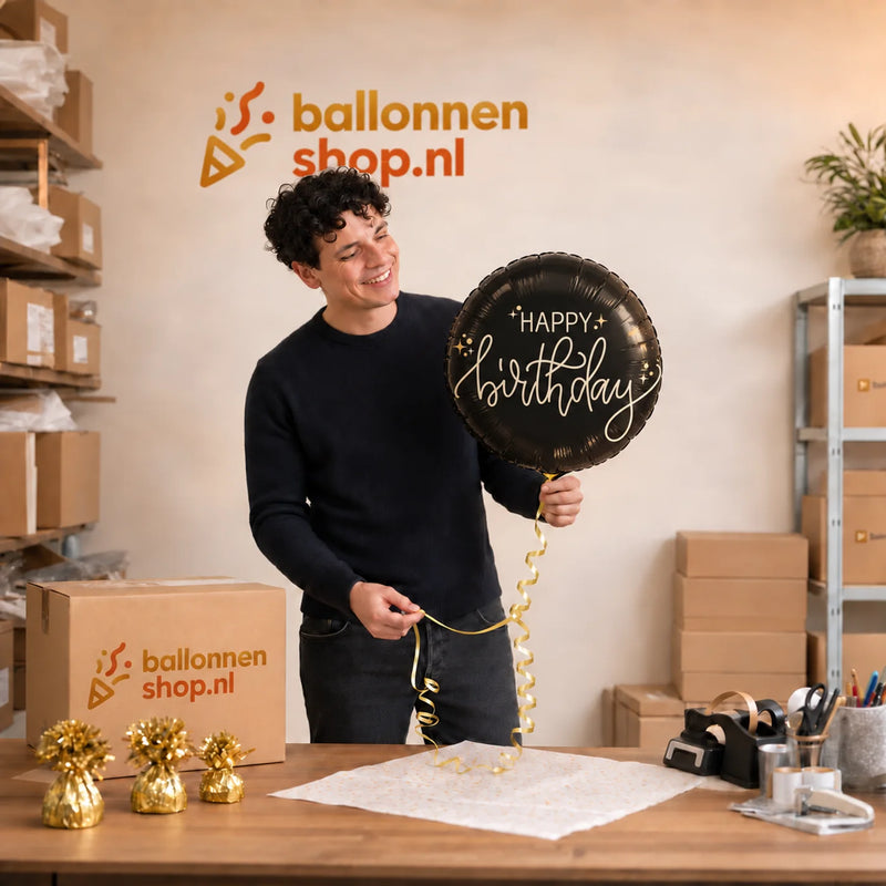 Jesse houdt de Happy Birthday Crème Noir Ballon vast in de warme werkplaats van Ballonnenshop.nl.