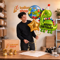 Jesse houdt het Happy Birthday Dino XL Trosje vast in de warme werkplaats van Ballonnenshop.nl