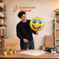 Jesse houdt de Happy Birthday Emoji Ballon vast in de warme werkplaats van Ballonnenshop.nl.