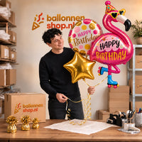 Jesse houdt het Happy Birthday Flamingo XL Trosje vast in de warme werkplaats van Ballonnenshop.nl