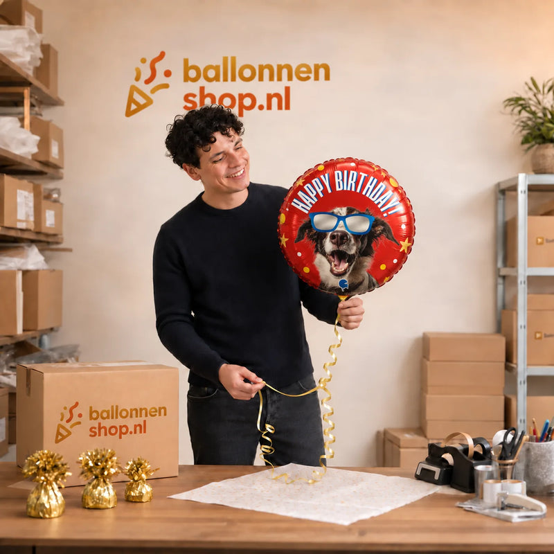 Jesse houdt de Happy Birthday Hond Ballon vast in de warme werkplaats van Ballonnenshop.nl.