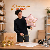 Jesse houdt de Happy Birthday Ster Licht Roze vast in de warme werkplaats van Ballonnenshop.nl.