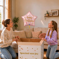 Meisje en moeder kijken naar een lichtroze Happy Birthday sterballon van 45 cm boven de cadeaudoos.