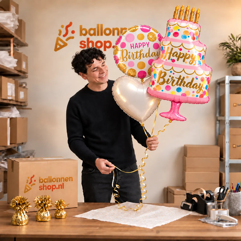 Jesse houdt het Happy Birthday Taart XL Trosje Roze vast in de warme werkplaats van Ballonnenshop.nl