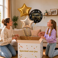 Happy Birthday Trosje Zilver/Zwart/Goud: moeder en dochter pakken het heliumgevulde ballonnentrosje uit een Speciaal voor jou-doos, met natuurlijk gekrulde gouden linten.