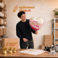 Jesse houdt de Happy Mother's Day Pretty Pink vast in de warme werkplaats van Ballonnenshop.nl.