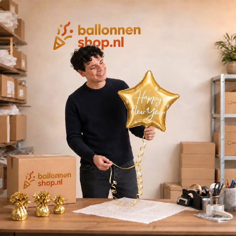 Jesse houdt de Happy New Year Ster Ballon Goud vast in de warme werkplaats van Ballonnenshop.nl.