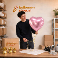 Jesse houdt de Hart Ballon Roze – 46 cm vast in de warme werkplaats van Ballonnenshop.nl.
