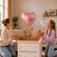 Roze hartjesballon van 46 cm zweeft boven een open cadeaudoos bij een moeder en meisje.