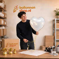 Jesse houdt de Hart Ballon Wit vast in de warme werkplaats van Ballonnenshop.nl.