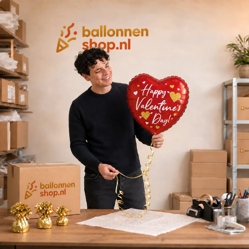 Jesse houdt de Happy Valentine’s Day Hartjes – Liefdevol Gebaar vast in de warme werkplaats van Ballonnenshop.nl.