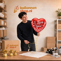 Jesse houdt de Hartjes Ballon I Love You – 43 cm vast in de warme werkplaats van Ballonnenshop.nl.