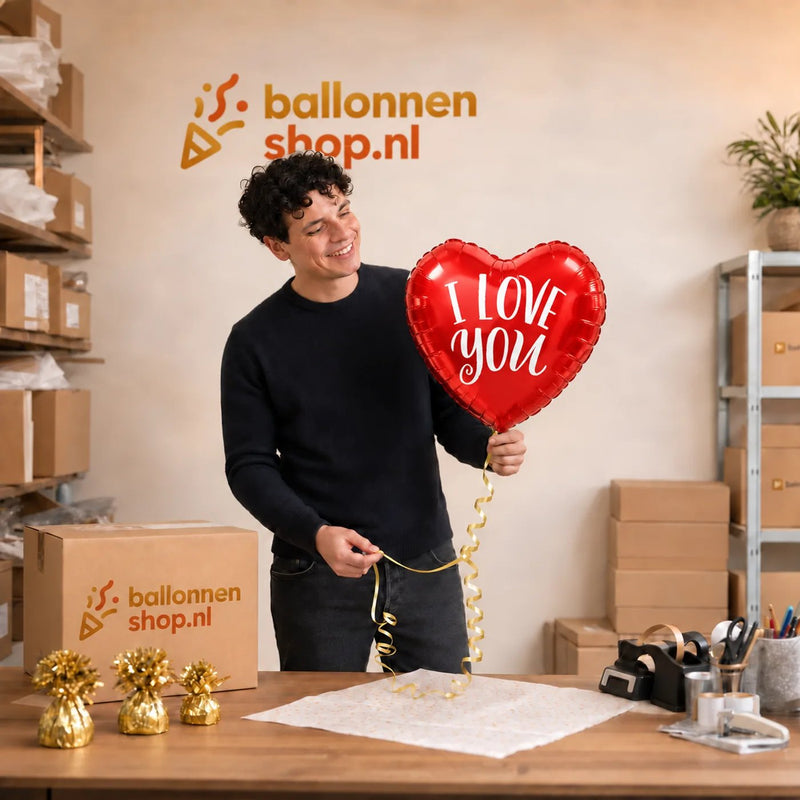 Jesse houdt de Hartjes Ballon I Love You – 45 cm vast in de warme werkplaats van Ballonnenshop.nl.