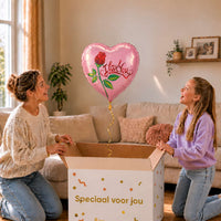 Moeder en meisje pakken een roze I Love You hartballon met een rode roos en groene bladeren uit de cadeaudoos.