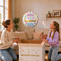 Moeder en meisje bekijken een witte Have a Magical Day heliumballon met pastelkleurige stippen en gouden letters.