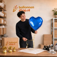 Jesse houdt de Helium Ballon Hart Blauw vast in de warme werkplaats van Ballonnenshop.nl.