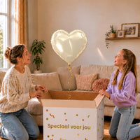 Moeder en meisje pakken een ivoorkleurige hartvormige heliumballon van 45 cm uit een cadeaudoos.