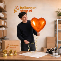 Jesse houdt de Helium Ballon Hart Oranje vast in de warme werkplaats van Ballonnenshop.nl.