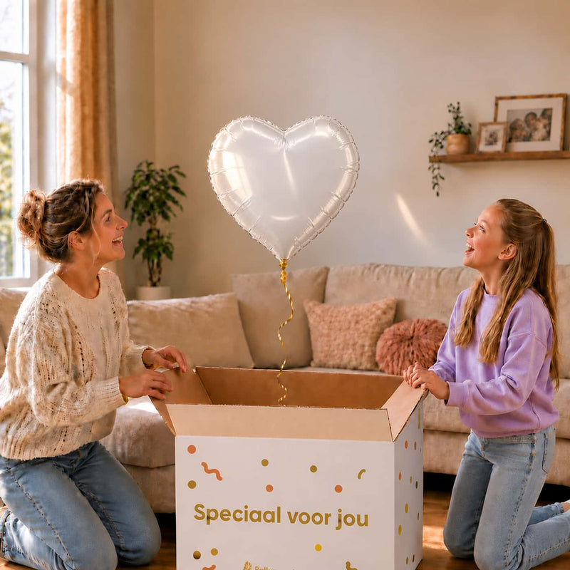 Moeder en meisje kijken naar een witte hartvormige heliumballon van 45 cm boven de open cadeaudoos.